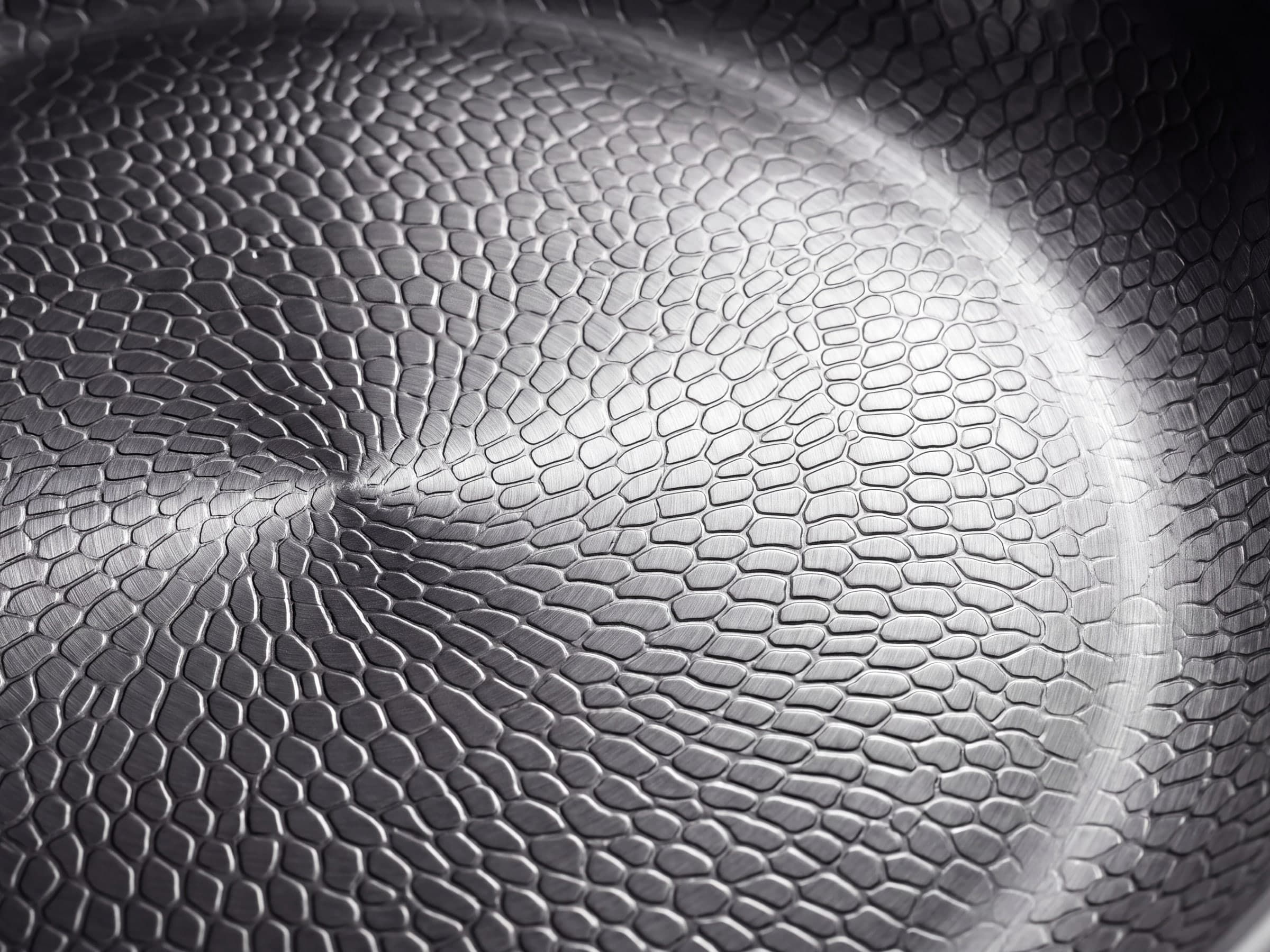 Macro of the hammered titanium cooking surface catching side light