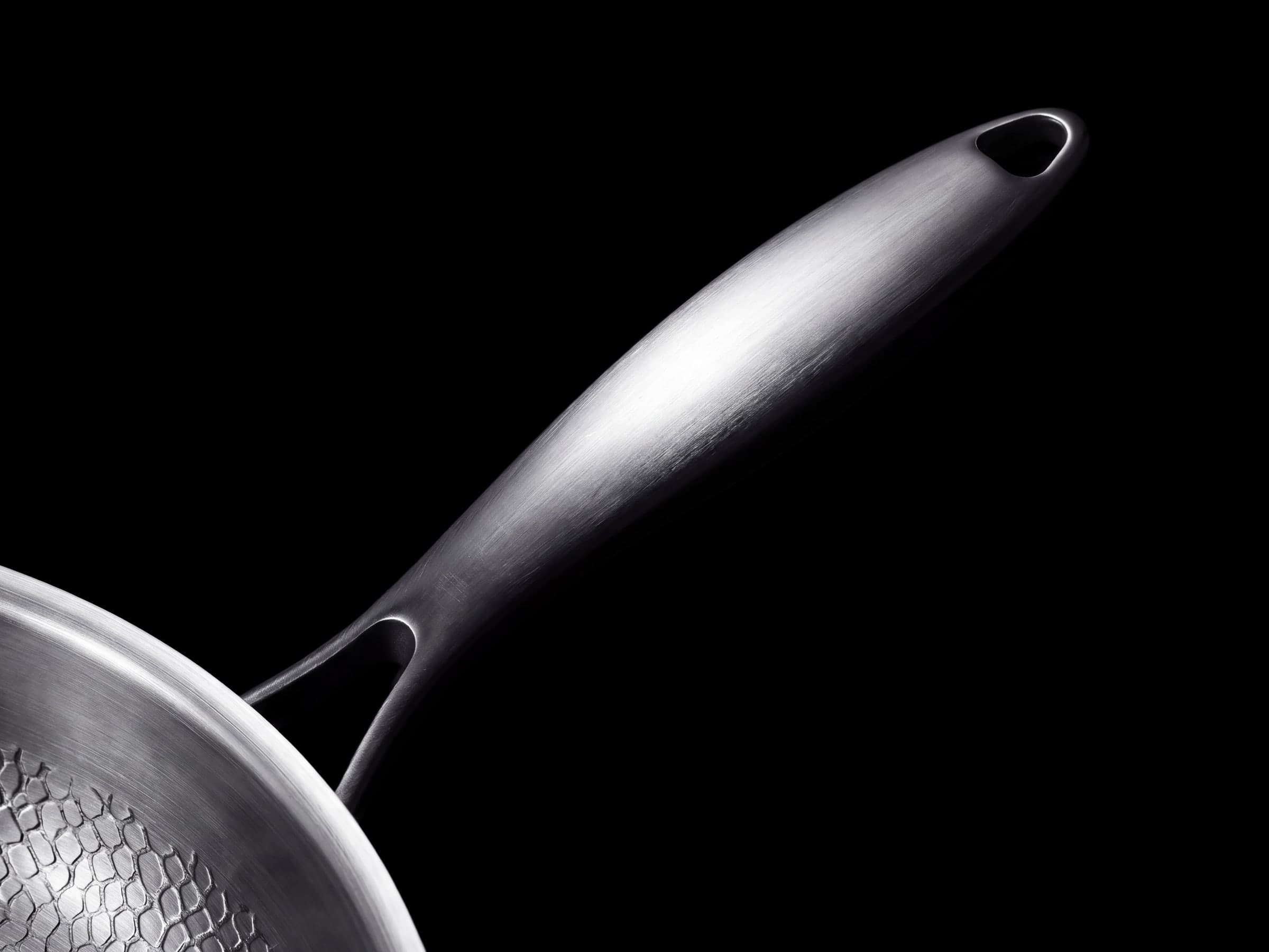 Brushed titanium handle rising from the rim of the pan